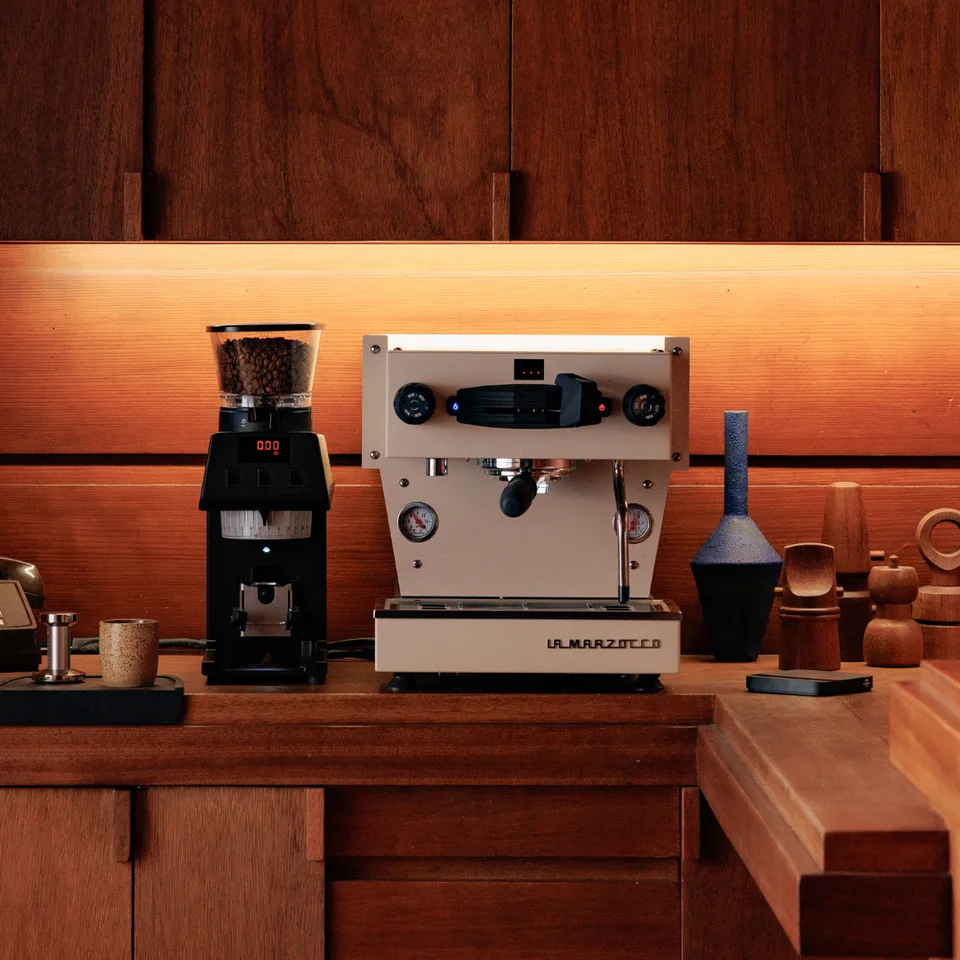 Crèmekleurige Linea Mini R naast een koffiemolen op een houten werkblad